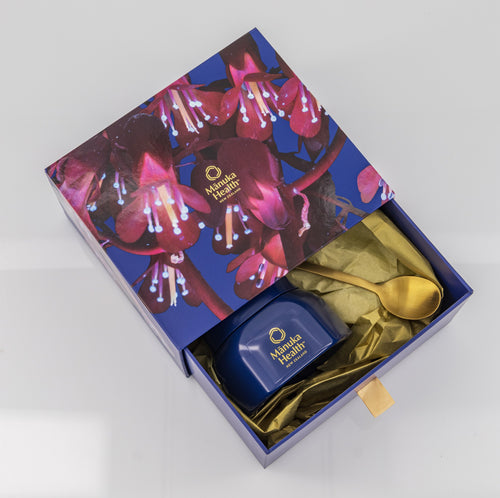 Minka Health Manuka Honey gift set with a blue box, gold spoon, and floral design on a white background.