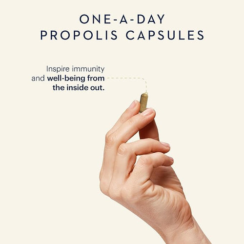 Hand holding a propolis capsule with promotional text on a light background