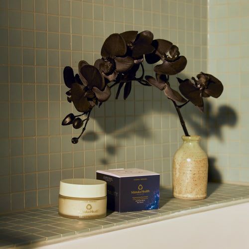 Manuka Health Eternal Renewal Face Cream jar with packaging and black flower adjust a sage tiled background. 
