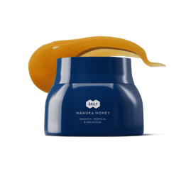Blue jar of Manuka honey with a swatch of honey on a white background.