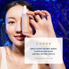 A woman holds up a small frosted serum bottle with a white dropper against a dark blue glittery background. A white review card with gold stars and text appears in the lower right, and the bottle label shows the brand name 'LUMIÈRE'.