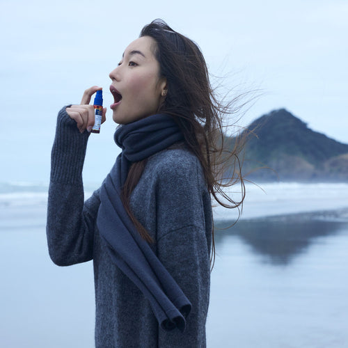 Woman using an inhaler with a mountain and lake in the background